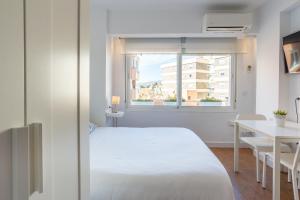1 dormitorio con cama, escritorio y ventana en LU&CIA Malagueta 9, en Málaga