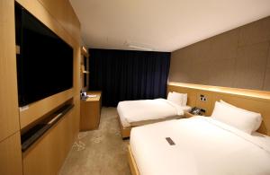 a hotel room with two beds and a flat screen tv at Sea Cruise Hotel in Sokcho