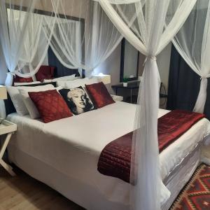 1 dormitorio con 1 cama blanca grande con cortinas en Monte Roza Guest House, en De Doorns