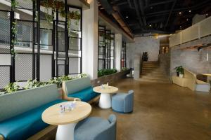 un vestíbulo con 2 mesas, sillas y plantas en Joylive BSD City, en Tangerang
