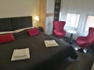 um quarto com uma grande cama preta e 2 cadeiras vermelhas em Filsdeger Royal Panzió em Eger