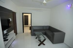 a living room with a couch and a glass table at Moonlight Residency in Tiruchirappalli