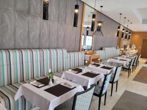 uma sala de jantar com mesas e cadeiras brancas em Hotel Tiba em Tunes