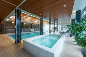 une piscine intérieure avec un bain à remous dans un bâtiment dans l'établissement Spa Hotel Runni Iisalmi, à Iisalmi