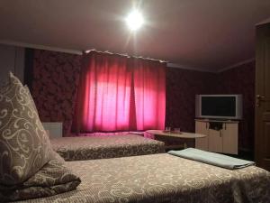 ein Schlafzimmer mit zwei Betten und einem rosa Vorhang in der Unterkunft Готелік in Drohobytsch