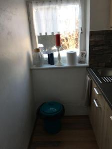 a small kitchen with a window and a blue stool at Evis Seehäusl in Übersee