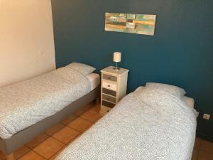 ein Schlafzimmer mit 2 Betten und einem Nachttisch mit einer Lampe in der Unterkunft Appartement "Jardins" in Pesmes