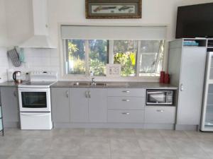 a kitchen with white appliances and a large window at Taipa Coastal Retreat in Taipa