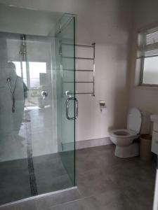 a bathroom with a glass shower and a toilet at Taipa Coastal Retreat in Taipa