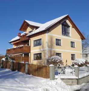 ein Haus mit einem Zaun im Schnee in der Unterkunft Ferienwohnung Brigitte Frank in Bärnau