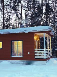 une petite maison rouge avec de la neige sur le toit dans l'établissement Cottages Sosnovo Life, à Snegirëvka