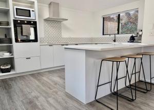 a kitchen with white cabinets and a counter with stools at Lakeview Oasis in Queenstown