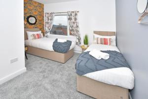 a bedroom with two beds and a window at A Cosy and Modern Mid-Terraced Retreat in Stoke! in Stoke on Trent