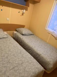 2 nebeneinander sitzende Betten in einem Schlafzimmer in der Unterkunft Mobil-Home 2 "Camping" in Pesmes