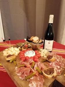 a cutting board with meat and vegetables and a bottle of wine at Chambre avec jacuzzi privatif "le pêcher" in Saillans