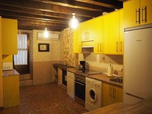 a kitchen with yellow cabinets and a washer and sink at El Rincón de Anter C in Cenicientos