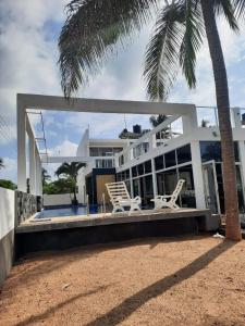 ein weißes Haus mit zwei Stühlen und einer Palme in der Unterkunft Saara Beach Hotel in Marawila