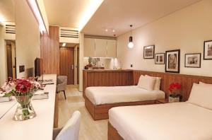 um quarto de hotel com duas camas e uma mesa com flores em Le Pave Residences em Bayt al Kūkū