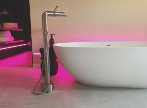 a white bath tub in a room with pink lighting at Home8 studio’s in Arnhem