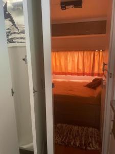a bedroom with a bed with an orange curtain at Trailer, Esporte e Amigos in Atibaia