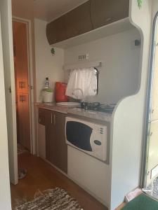 a small kitchen with a stove and a microwave at Trailer, Esporte e Amigos in Atibaia