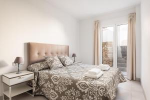 a white bedroom with a large bed and a window at Villa La Plaza in Fornells