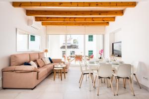 a living room with a couch and a table and chairs at Villa La Plaza in Fornells