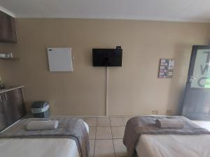 Cette chambre comprend 2 lits et une télévision murale. dans l'établissement DeLutz Overnight Accommodation Room 2, à Polokwane