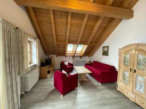 a living room with red furniture and a wooden ceiling at Ferienwohnung Fauser in Oberstdorf