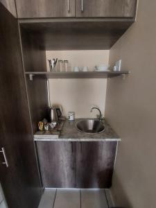 eine kleine Küche mit Spüle und Regalen in der Unterkunft DeLutz Overnight Accommodation Room 2 in Polokwane