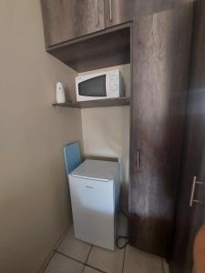 eine kleine Küche mit einem Kühlschrank und einer Mikrowelle in der Unterkunft DeLutz Overnight Accommodation Room 2 in Polokwane