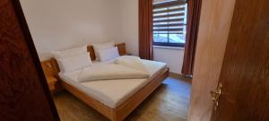 sypialnia z łóżkiem z białą pościelą i oknem w obiekcie Ferienwohnung 3 Personen Alleinlage auf 1500m am Waldrand und Skigebiet Hochzeiger w mieście Jerzens