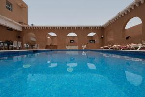 une grande piscine bleue dans un bâtiment dans l'établissement Hotel Al Massira, à Laâyoune