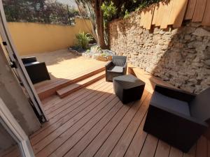 un patio avec deux chaises et des chaises sur une terrasse en bois dans l'établissement Inviting 1-Bed Apartment in Grezieu-la-Varenne, à Grézieu-la-Varenne