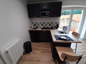 a kitchen with black cabinets and a table and chairs at Inviting 1-Bed Apartment in Grezieu-la-Varenne in Grézieu-la-Varenne