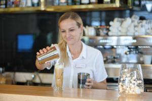 a woman standing behind a counter pouring a drink at Seasabelle Hotel near Athens Airport in Artemida