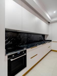 a kitchen with white cabinets and a black stove top oven at Vida Herastrau, luxury 2 rooms apartment in Bucharest