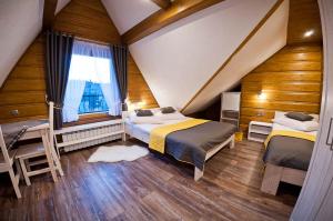 een slaapkamer op zolder met 2 bedden en een raam bij Dom Wczasowy Na Polanie in Ciche Małe