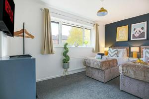 a bedroom with a bed and a couch and a window at Pannier House - Central MK - Free Parking, Garden, Smart TVs with Netflix by Yoko Property in Milton Keynes