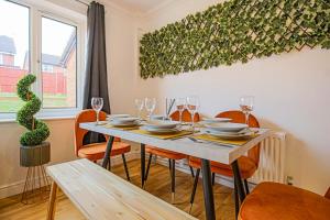 a dining room with a table with chairs and glasses at Pannier House - Central MK - Free Parking, Garden, Smart TVs with Netflix by Yoko Property in Milton Keynes