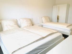 two beds with white sheets and pillows in a room at Ganzes Apartment 20 min vom Frankfurt HBF in Langen