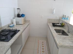 a white kitchen with a sink and a stove at Casa azul in Barra do Garças