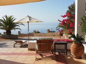 a patio with a table and chairs and an umbrella at Tranquil Villa with Sea view in Ammopi Karpathos in Amoopi