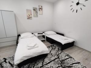 a room with two beds and a clock on the wall at Apartament Sikorki in Nowy Sącz