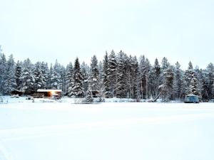 a snow covered field with a forest of trees at Lapland Northern Lights Cabin - Wooden Sauna in Rovaniemi