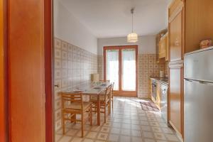 La cuisine est équipée d'une table, de chaises et d'un réfrigérateur. dans l'établissement Incantevole Villa Margherita x4 ad Aurisina, à Aurisina