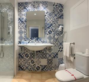 a bathroom with a sink and blue and white tiles at Hostal HPC Porto Colom in Portocolom