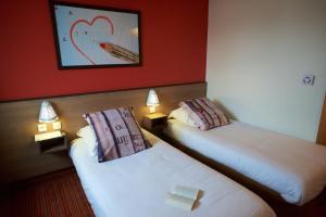 two beds in a room with red walls at Ace Hotel Annecy in Annecy