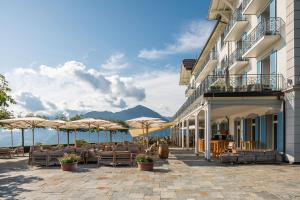 a hotel with tables and chairs and umbrellas at Hotel Villa Honegg in Ennetbürgen