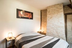 a bedroom with a bed and two lamps and a stone wall at Maison de ville NLR - 6 lits simples - BBQ - Proche Gare - grand Parking in Nogent-le-Rotrou